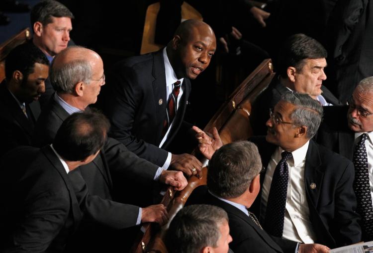 TEA PARTY: U.S. Rep. Tim Scott (R-S.C.) (C) talks with U.S. Rep. Bobby Scott (D-Va.) during the first session of the 112th Congress in the House chamber Jan. 5 in Washington. A Tea Party favorite, Rep. Tim Scott stood with Democrats during most of the first session.  (Alex Wong/Getty Images)