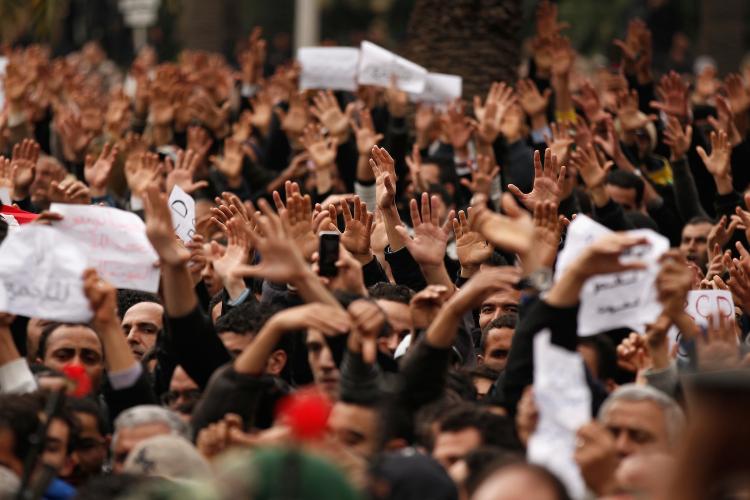 Tunisian demonstrators gesture with their hands calling to the army to pull down the Constitutional Democratic Rally (RCD) party headquarters sign on January 20, 2011 in Tunis, Tunisia. The success of Tunisia's Jasmine Revolution has caught the world's attention including the Chinese. (Christopher Furlong/Getty Images)