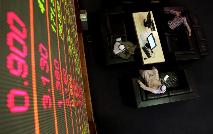 Emirati men sit under a stock market screen at Dubai Financial Market, on January 30, 2011. (Karim Sahib/AFP/Getty Image)