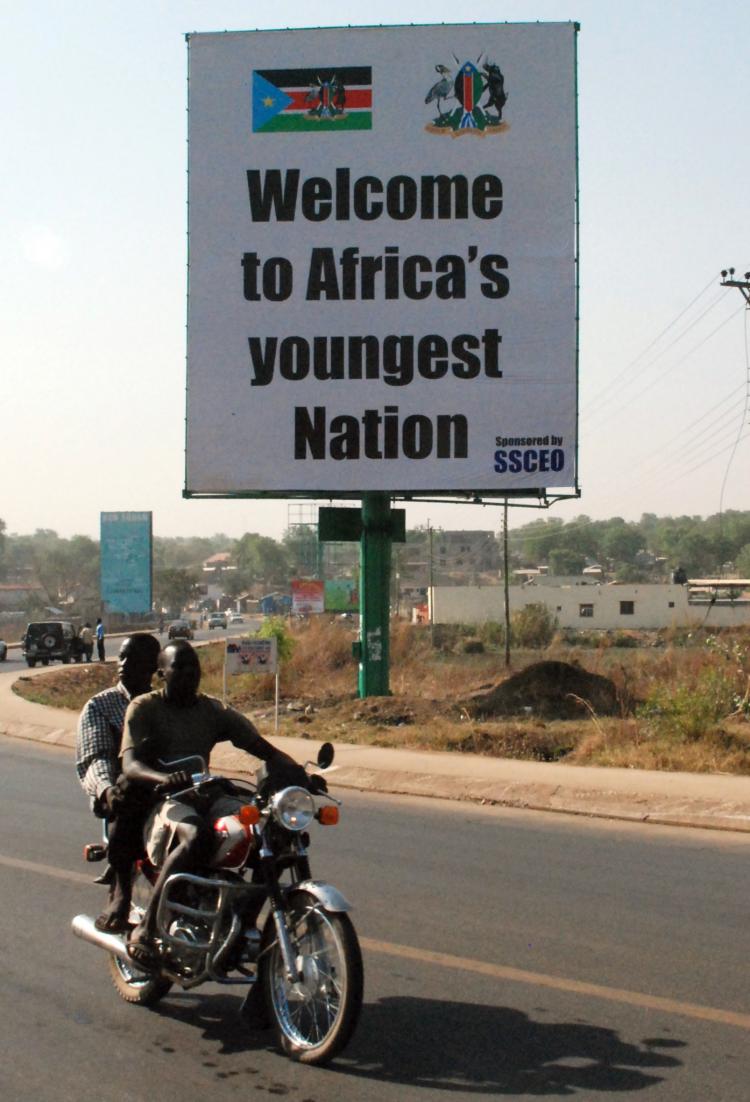 Southern Sudanese men ride a motorcycle past a billboard celebrating the choice of the south to separate Africa's largest nation in two in the southern Sudanese capital Juba on February 7, 2011 hours before the expected announcement of the landmark independence referendum's final results.(Peter Martell/Getty Images)