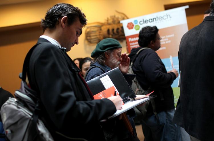 Job applicants take notes while they wait in line for a meeting with a recruiter. (Justin Sullivan/Getty Images)