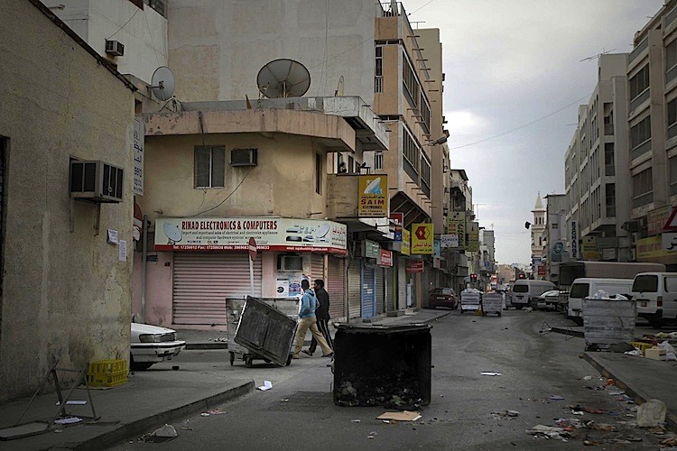 Bahraini youths walk past garbarge containers blocking streets during curfew hours in the capital Manama on March 16, after government forces raided a month-old pro-democracy sit-in.  (Joseph Eid/AFP/Getty Images)