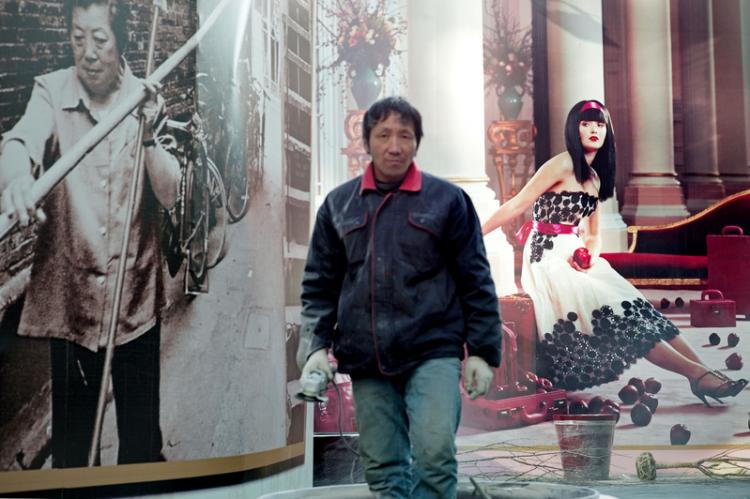 A worker stands in front of a poster of a luxury real estate project in Shanghai, China, Jan. 2011.  (Getty Images)