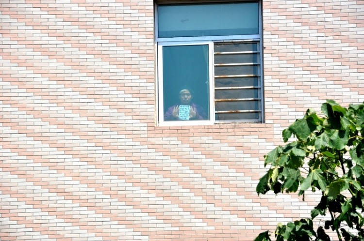 To communicate with his brother, Li Jinlong shows a placard from a hallway window on the third floor of the Chaoyang District Mental Hospital. (Photo provided by Li Jinping)