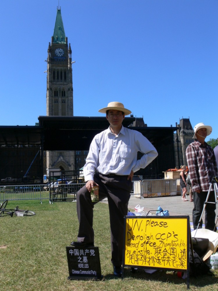 Zhang Xiangyang, a Toronto resident, steps on a symbolic CCP tombstone to protest the forced demolition of his home in China.  (Wu Wei/The Epoch Times)