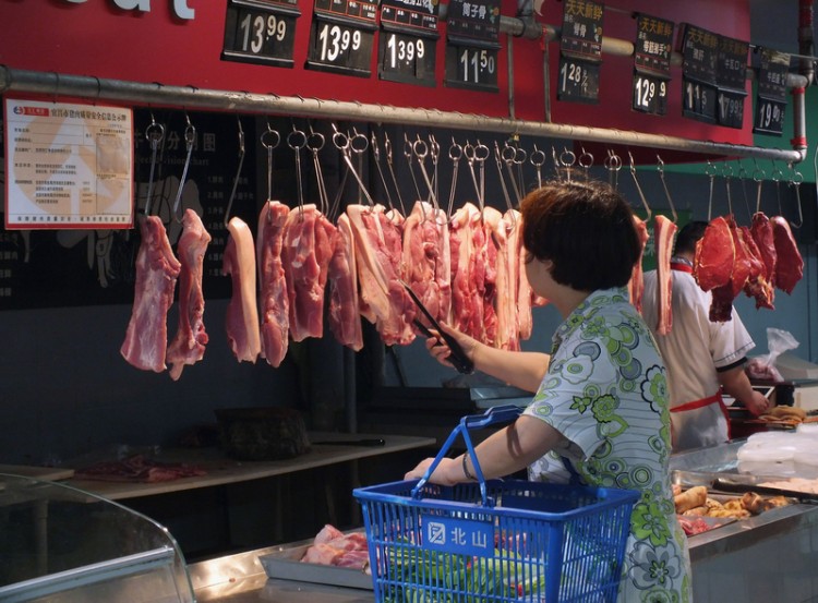 Shopper carefully selects her pork as prices have rocketed 50 percent in one year. (Chinafotopress/Getty Images)