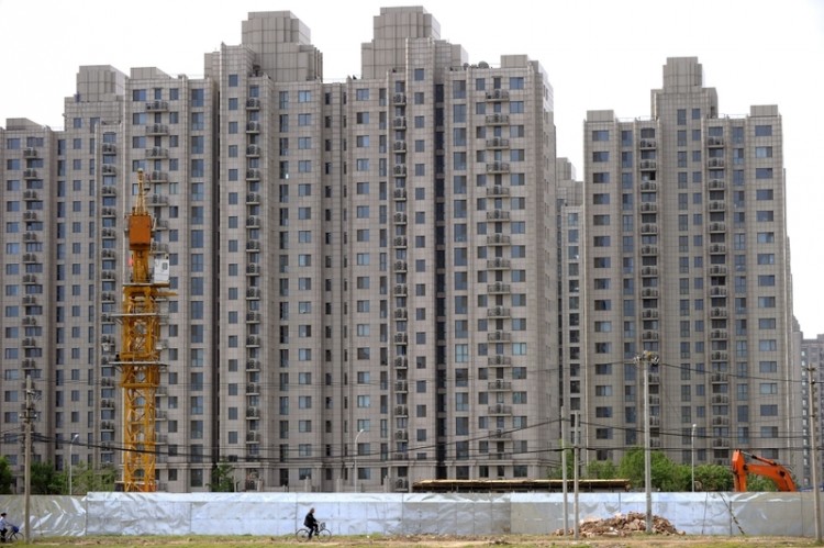 A man on a bicycle is riding past a real-estate development in Beijing. (Getty Images)