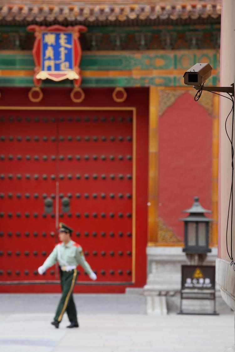 A paramilitary policeman patrols at the entrance of the Forbidden City Palace Museum on May 18 in Beijing. A security camera is visible in the top right hand corner of the photo. (Feng Li/Getty Images)