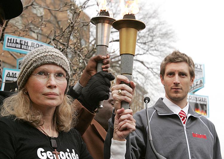 Actress Mia Farrow (L) holds an Olympic-style torch with Olympic speed skater Joey Cheek (R), after arriving at China's embassy as part of a march sponsored by the Save Darfur Coalition to mark International Human Rights Day with a Dream for Darfur Torch  (Saul Loeb/AFP/Getty Images)