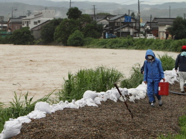 Local residents walk on a bank of the Igarashigawa River swollen with heavy rain in Sanjo, Niigata Prefecture, on July 30. (Jiji Press/AFP/Getty Images)
