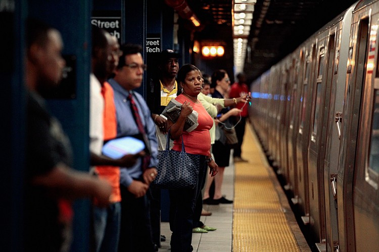 Commuters prepare to board the F train at the Jay Street subway station