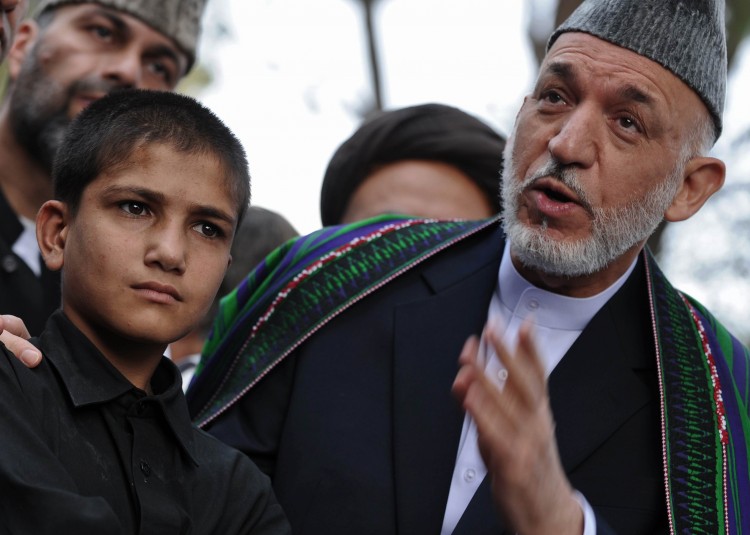 Afghanistan's President Hamid Karzai (C) pardons a would-be child suicide bomber during a ceremony following Eid al-Fitr prayers at the Presidential Palace in Kabul on August 30, 2011. (Massoud Hossaini/AFP/Getty Images)