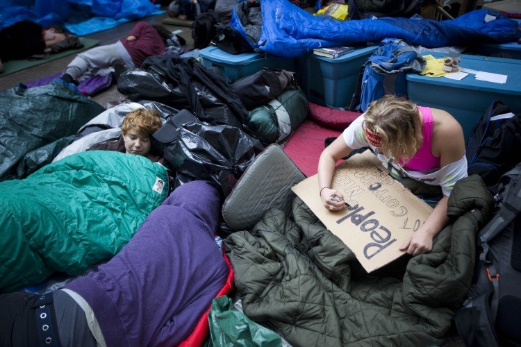 An Occupy Wall Street demonstrator makes a sign as others sleep in Zuccotti Park after marching in the financial district on October 14, 2011 in New York City. (Michael Nagle/Getty Images)