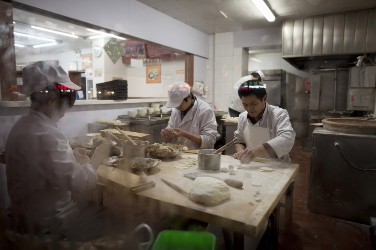 Chefs make dumplings inside a restaurant