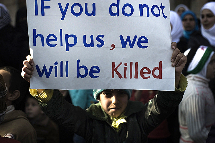 A young boy holds up a sign during an anti-Syrian regime demonstration