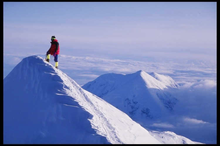 A lone climber stands on the Summit Ridge at Denali on Mount McKinley, Alaska