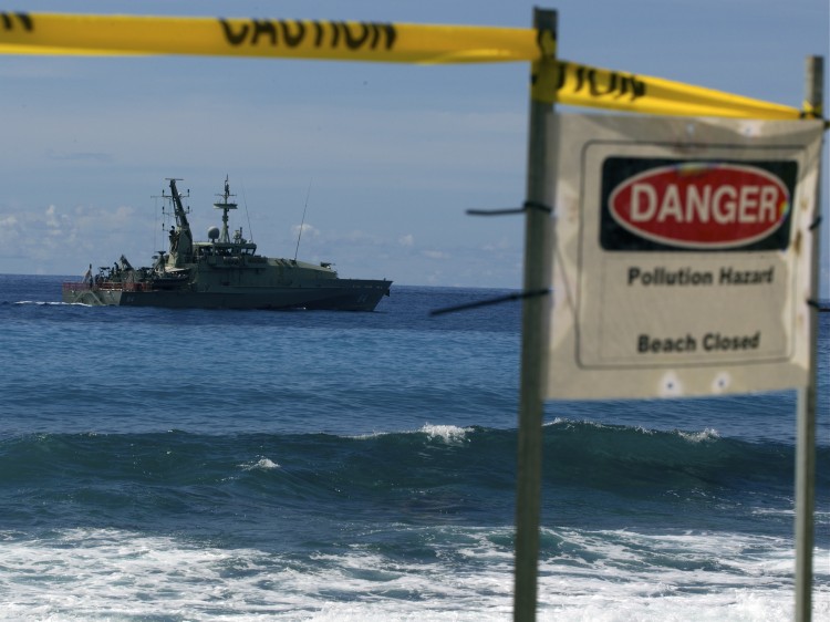 Australian Navy boat cruises by a closed beach 