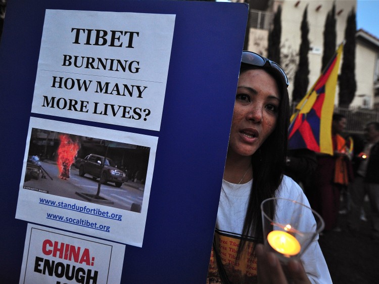 Tibetans and supporters of a 'Free Tibet' hold placards during a candlelight vigil