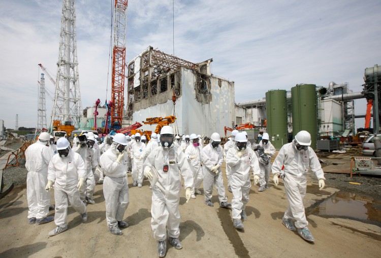 Members of the media and Tokyo Electric Power Co. (Tepco) employees look at the No. 4 reactor building (rear), amongst tsunamai damage, at the company's Fukushima Daiichi nuclear power plant in Okuma Town, Fukushima Prefecture on  May 26, 2012. (Tomohiro Ohsumi/AFP/GettyImages)