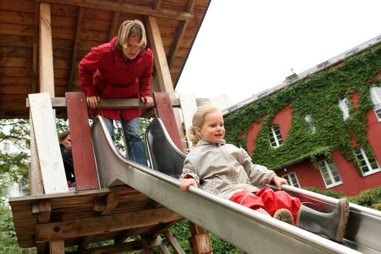 A mother and her three-year-old daughter play on a slide on a playground on June 6