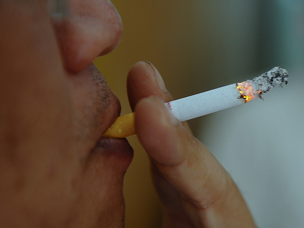 A man smokes a cigarette at a coffee shop