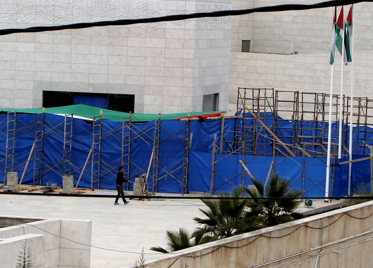 A Palestinian worker walks with a water hose in front of the tarpaulin hiding the mausoleum of the late Palestinian leader Yasser Arafat, on Nov. 27, at the Muqataa in the West Bank city of Ramallah. (Ahmad Gharabli/AFP/Getty Images) 