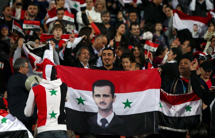 A Syrian man waves his national flag bearing the image of embattled President Bashar al-Assad during his country's team match against Iraq in the 7th West Asia Football Federation (WAFF) championship in Kuwait City on December 13, 2012.  (Marwan Naamani/AFP/Getty Images)