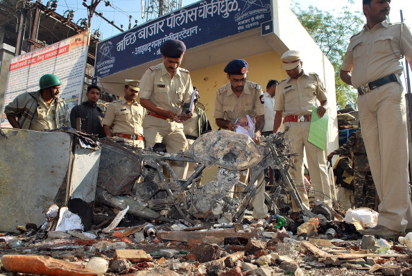 Indian police officials inspect a damaged vehicle at the site of clashes the previous day in Dhule district in Maharashtra state on Jan. 7, 2013.  (STR/AFP/Getty Images)