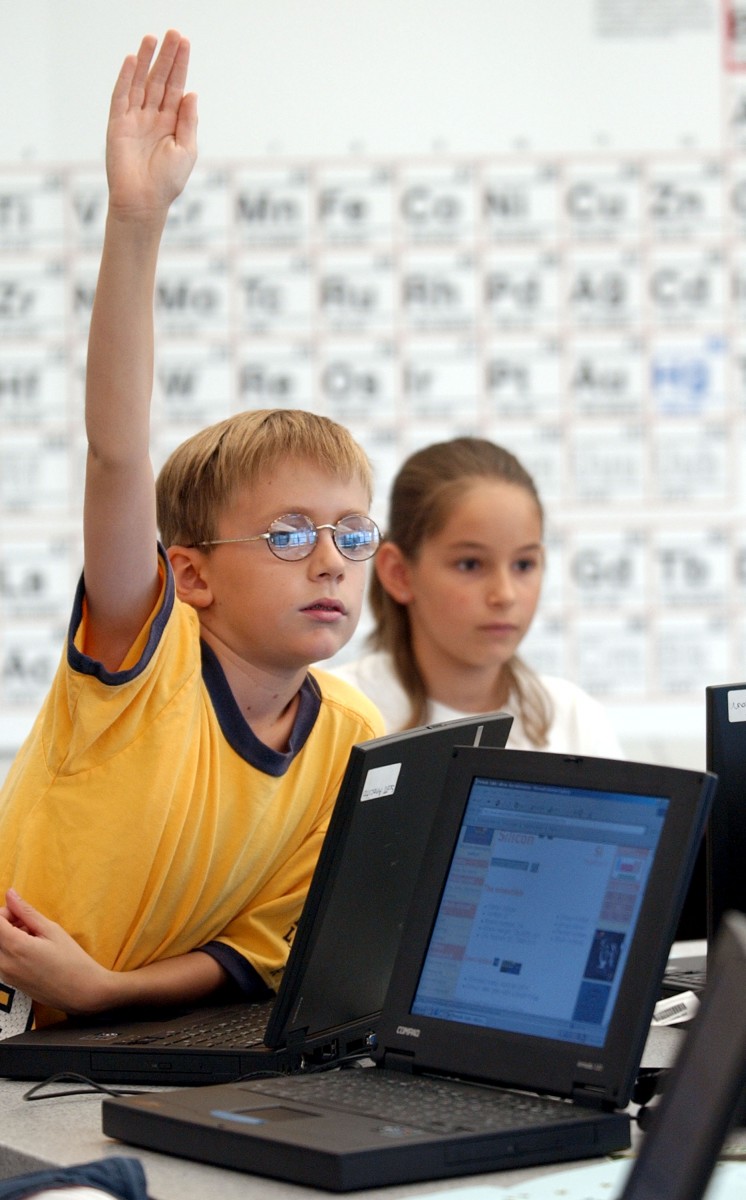 A student raises his hand during science class at the Discovery Charter School