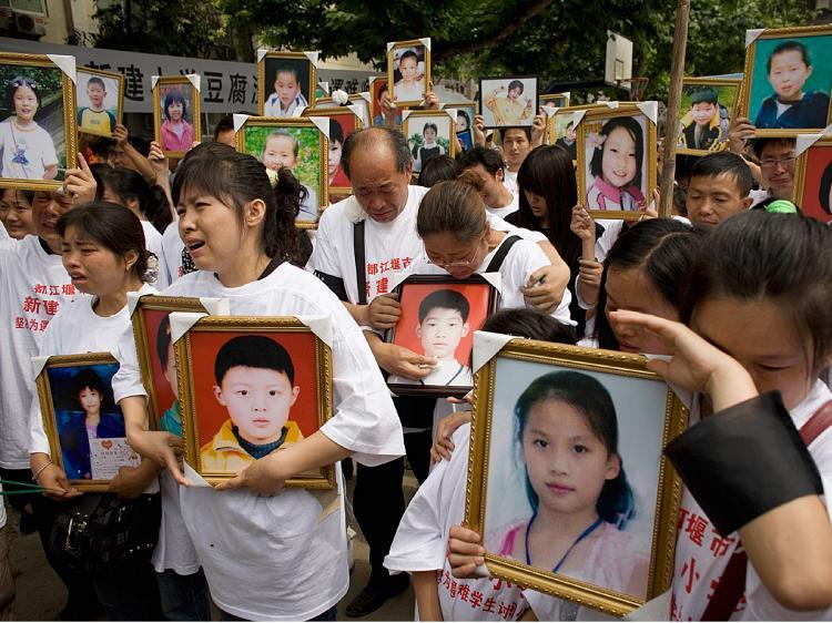 Parents of pupils killed when the Xinjian primary school collapsed in the May 12 earthquake cry as they hold portraits of their loved ones during a commemoration of Children's Day on the rubble-strewn school campus on June 1, 2008 in Dujiangyan, China. (Andrew Wong/Getty Images)