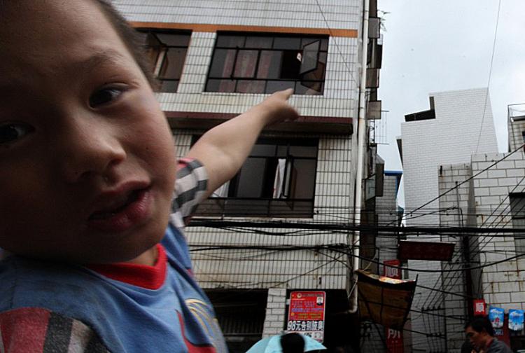 After the earthquake on August 30, a child points a obviously inclined building.   The Epoch Times (The Epoch Times)