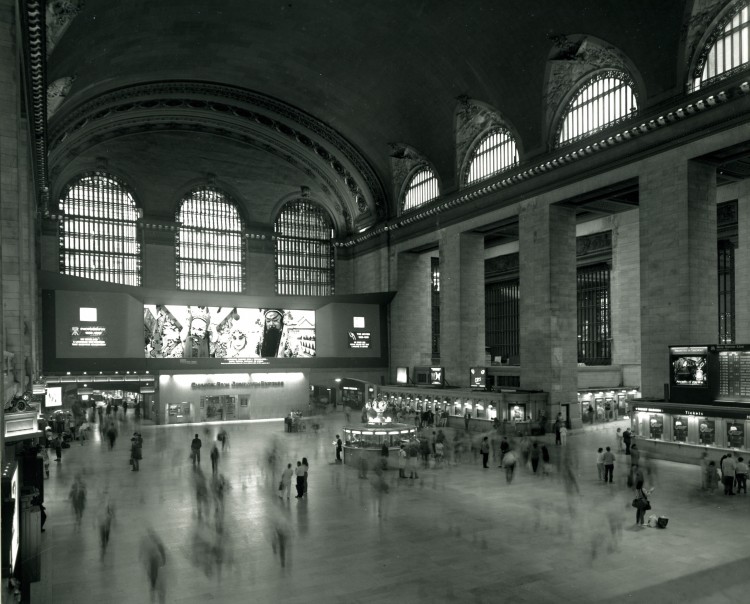  This is View of the main concourse of the Grand Central Terminal around 1980's. Note the nearly pitch black color of the ceiling, which would take a year to wash clean during the renovation. The Kodak panorama advertisement and the bank branch beneath it would be removed during the renovation to make way for a new marble staircase. (Courtesy of MTA/MetroNorth Railroad)