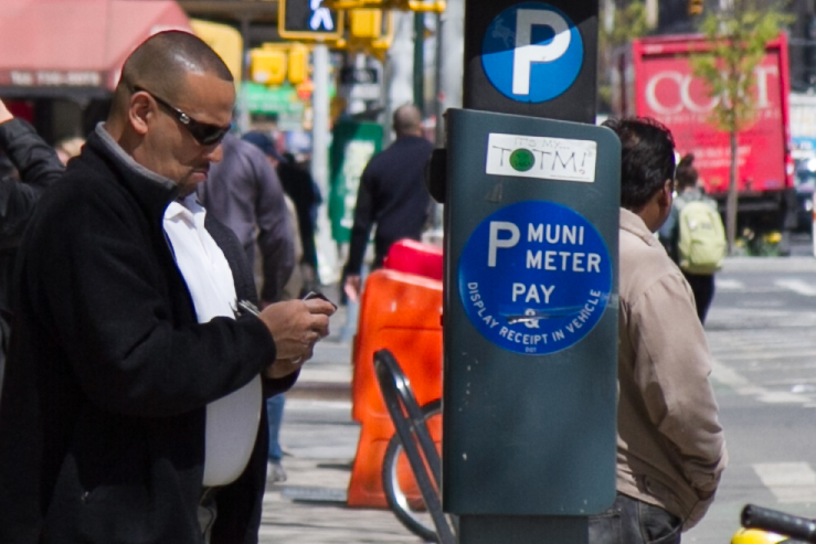 A man pays for parking at a Muni parking meter in Midtown Manhattan