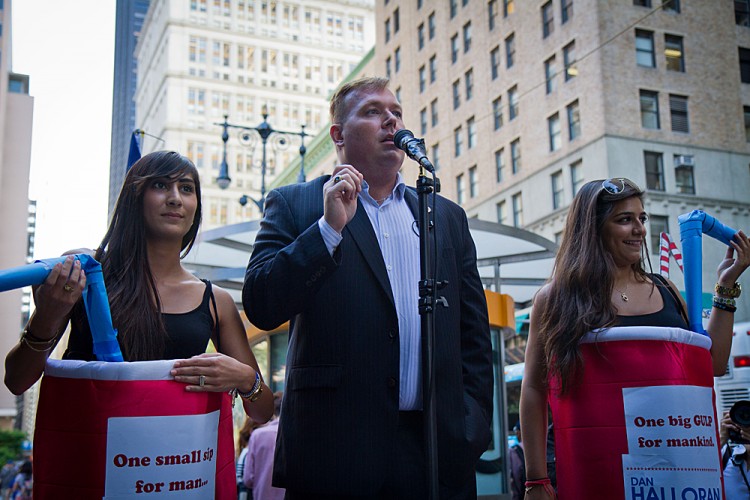 New York Councilman Dan Halloran, joined by two women in soft-drink cup costumes, speaks against Mayor Bloomberg's soda ban