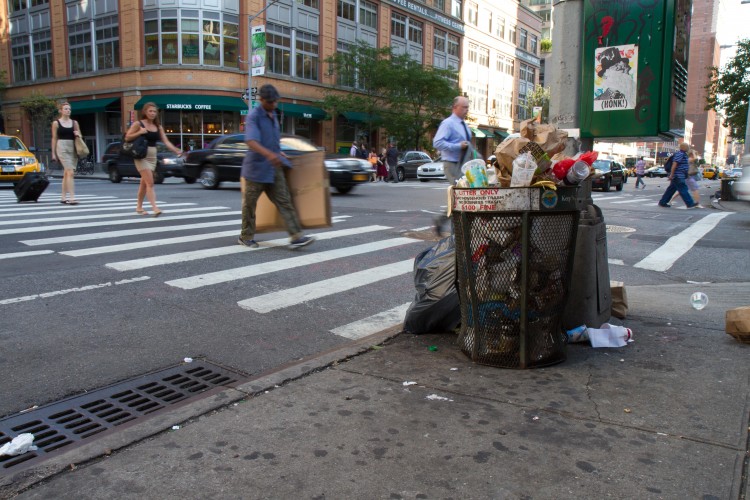 Trash falls out of a full garbage bin on Seventh Avenue in Midtown Manhattan Tuesday. According to New York City environmental protection commissioner, there is a chance that trash laying in the city's streets could end up on New York's beaches. (Benjamin Chasteen/The Epoch Times)