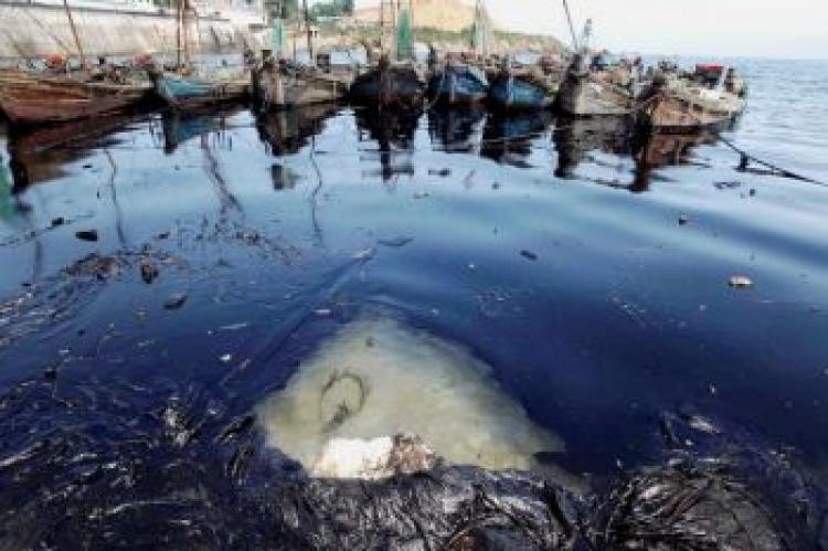 A boat and debris floating in an oil slick in the Yellow Sea, after a huge spill following the pipeline fire at the port in Dalian, in Liaoning Province, China. (AFP/AFP/Getty Images)