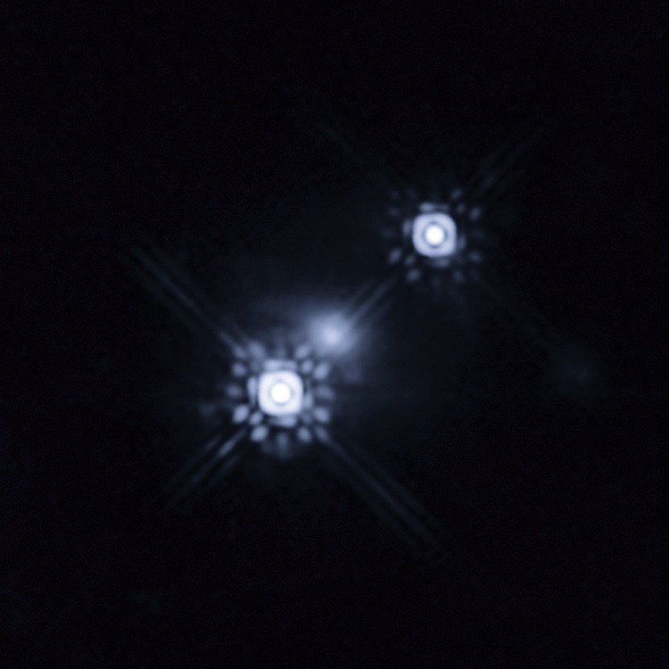 Image of a quasar that has been gravitationally lensed by a galaxy in the foreground, which can be seen as a faint shape around the two bright images of the quasar. Observations of one of the images show variations in color over time. (NASA, ESA, J.A. Munoz/University of Valencia)