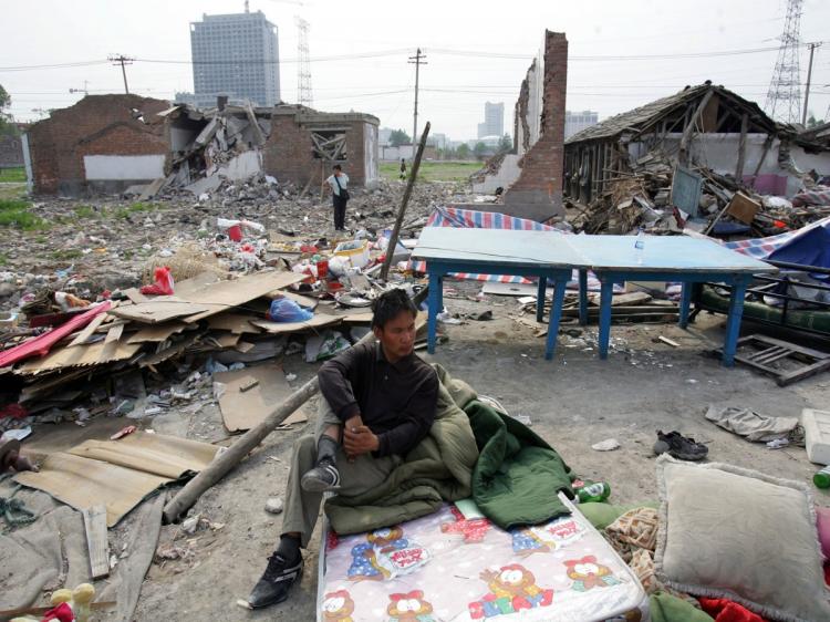 A resident sits on a mattress where his house was located, at the Taiyangong area on May 10, 2007 in Beijing. Some 26 bungalows were torn down at midnight on May 9 by unidentified people. Housing reform in China has seen the demolition of people's homes (China Photos/Getty Images)