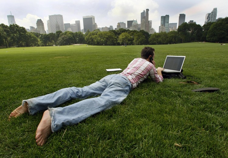 A man works on his laptop while he takes a break in the Sheep Meadow in Central Park in New York. (Timothy A. Clary/Getty Images)