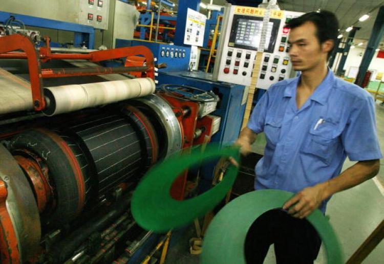 A worker from the Hangzhou Zhongce rubber company pieces together the different sections of a tyre at their factory in Hangzhou, 25 July 2007. (Mark Ralston/AFP/Getty Images)