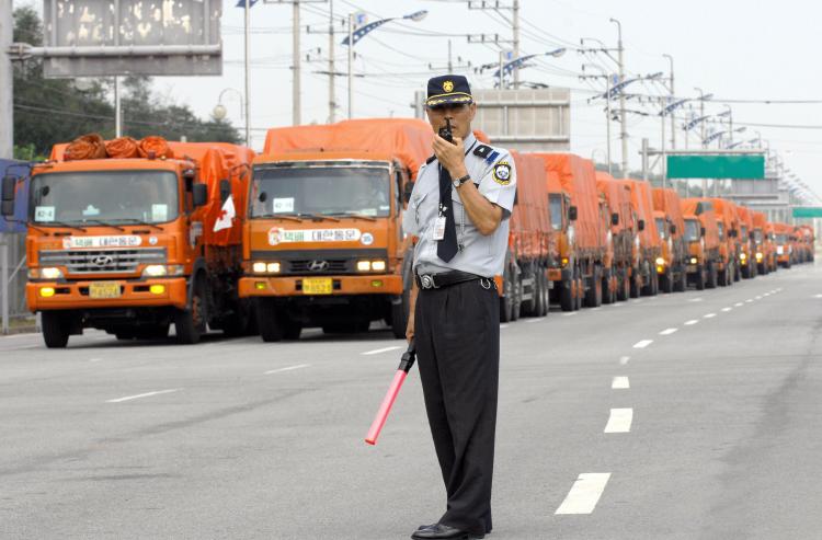 A South Korean security man talks over the radio as trucks carrying aid supply kits for North Korean flood victims wait at a checkpoint in August 2007. Widespread floods left more than 600 dead or missing and devastated crops and infrastructure. (JUNG YEON-JE/AFP/Getty Images))