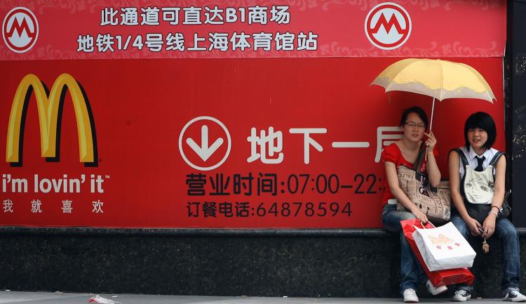 Two women site next to a huge McDonalds advertisement in Shanghai, in 2007. McDonald's Corp. said on Wednesday that it would open 200 new store locations in China to expand its operations in the world's most populous country.   (Marcus Brandt/Getty Images )