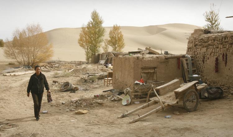 A local walks along the edge of the desert engulfing China's northwest Gansu Province. (Peter Parks/AFP/Getty Images)