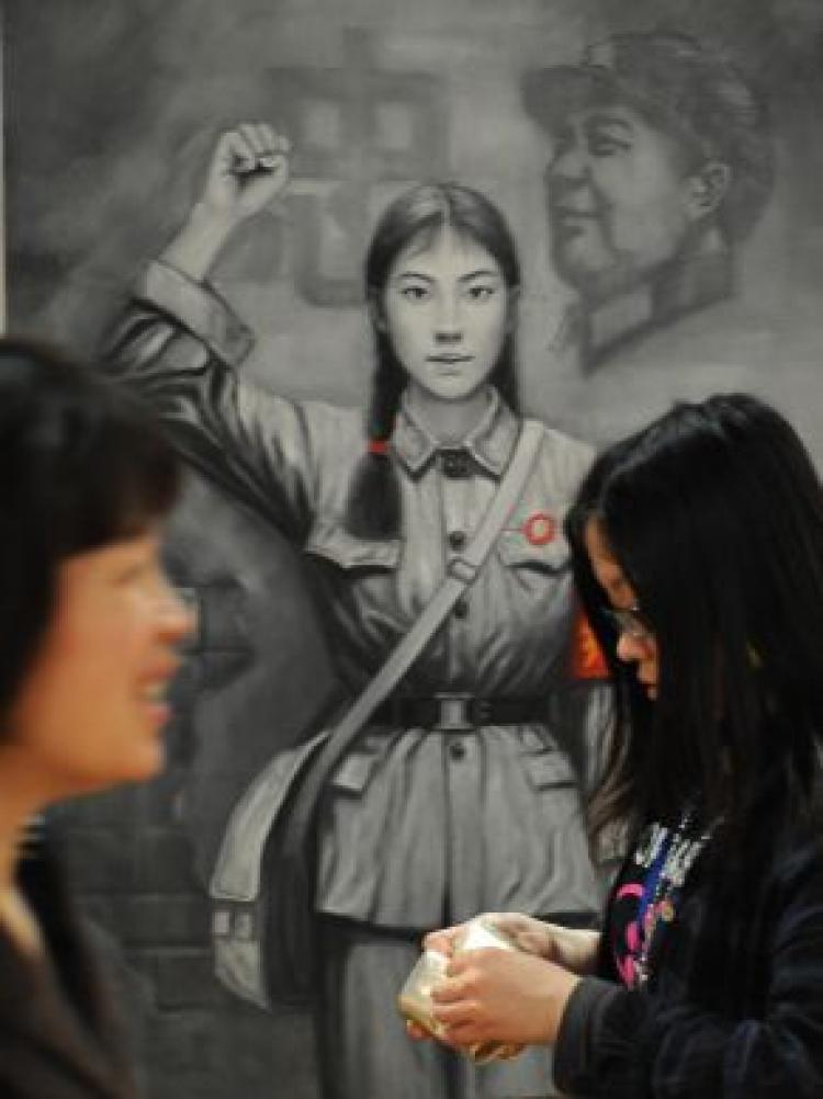 Two Chinese women walk past a painting of a Red Guard from China's Cultural Revolution period at an art exhibit in Shanghai. Parts of a 1950s devotional hymn to the Chinese Communist Party were changed or cut for the Olympics opening ceremony and internet censors have worked hard to keep stories of the singer switch off Chinese websites. (Mark Ralston/AFP/Getty Images)