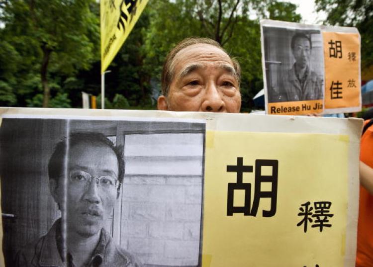 An elderly man holds a placard with the image of jailed Chinese rights campaigner Hu Jia.  (Andrew Ross/AFP/Getty Images)