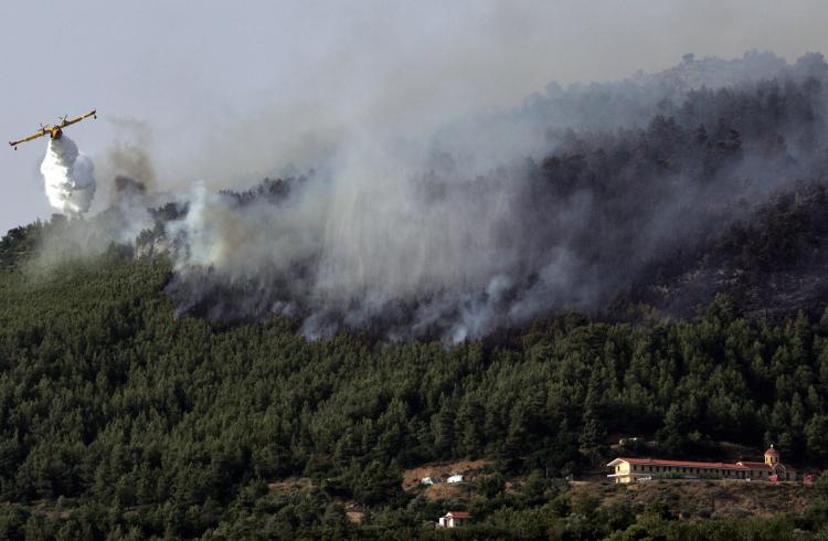A firefighting plane drops water on a burning forest on July 15, 2008, near the village of Oinoi, in Viotia region, central Greece. Greek firefighters struggled on July 15 to contain a major forest fire that broke out northwest of Athens and was being fan ((AFP PHOTO/ LOUISA GOULIAMAKI) )