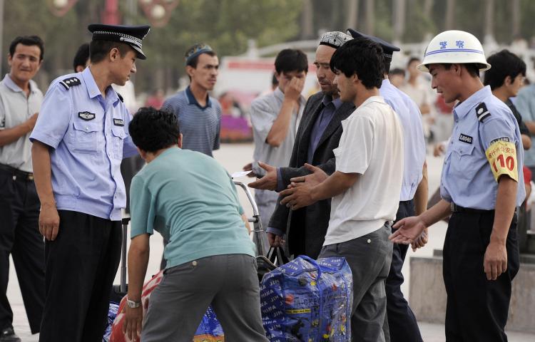 Police check identity cards of ethnic Uyghurs and search their bags in Xinjiang in China's far northwestern, mainly Muslim region.  (Peter Parks/AFP/Getty Images)