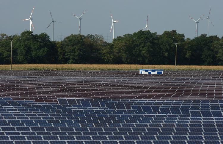 Renewable Energy: Wind turbines spin behind a field of solar cell panels. In 2010, investments in renewable energy sources, including wind, solar, and ocean power, will soar to $5 billion.  (Sean Gallup/Getty Images)