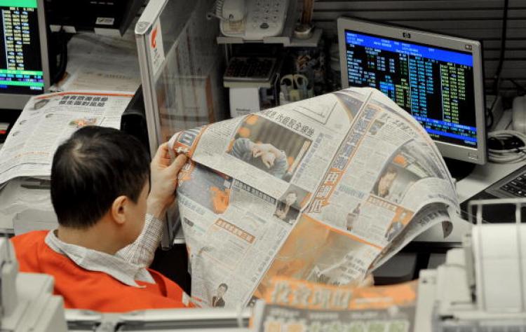 A trader reads newspaper at the Hong Kong Stock Exchange. ( Mike Clarke/AFP/Getty Images)