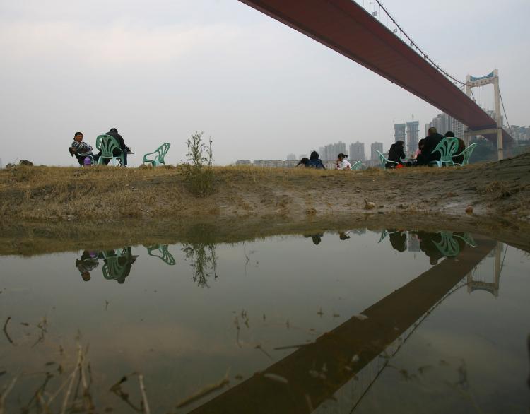 Residents drink tea beneath a bridge across the Yangtze River on November 28, in Chongqing. The Yangtze River has reached its flood peak this week.  (China Photos/Getty Images)